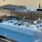 two-tier surgical back table in operating room set up with a blue sterile drape and surgical instruments