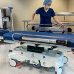 person in blue scrubs and a blue scrub cap standing behind a Pedigo Products stretcher in an Operating Room
