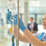 person with blue gloves checking iv bag